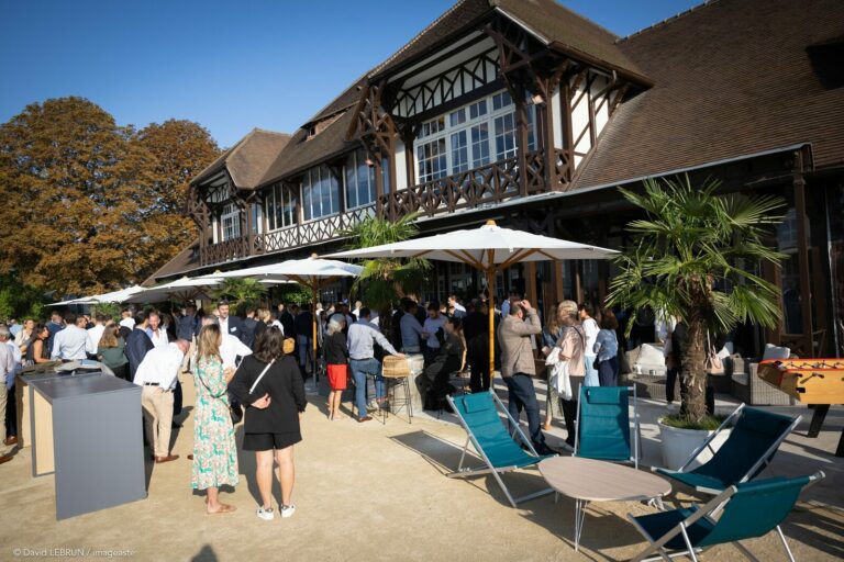 Cocktail extérieur convention REXEL 2023, invités sous parasols devant pavillon, mobilier lounge événementiel B2B