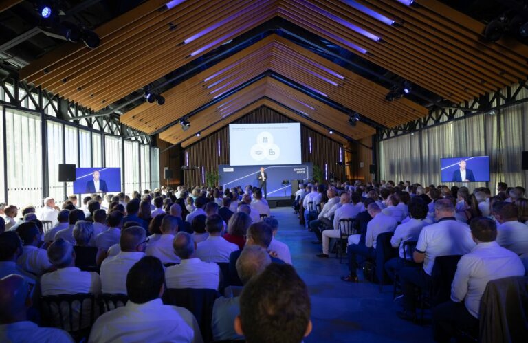 Plénière convention REXEL 2023, salle bois, écran central, audience corporate, scénographie événementielle B2B