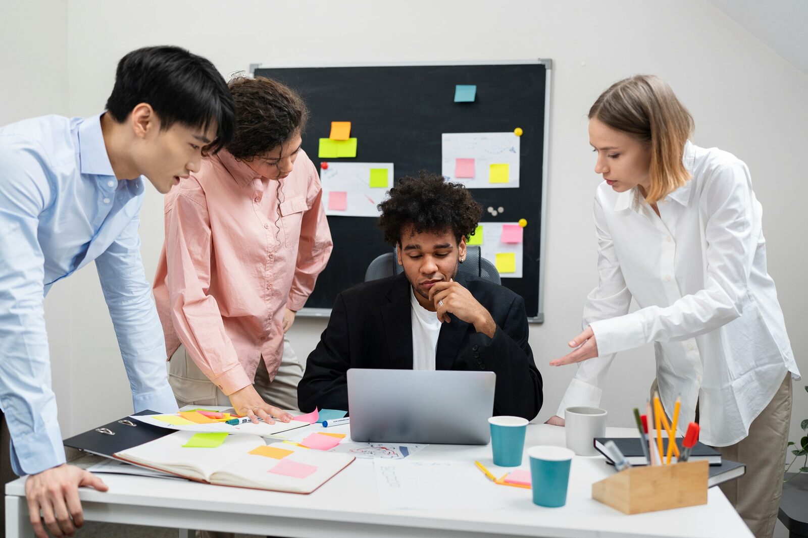 Reunion d'equipe projet evenementiel autour d'un ordinateur portable, post-it et planning, agence production TDN
