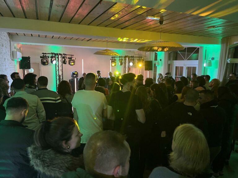 Soiree corporate BEL BRM 2025, plenière lumières vertes et ambres, public dense devant scène et régie lyres