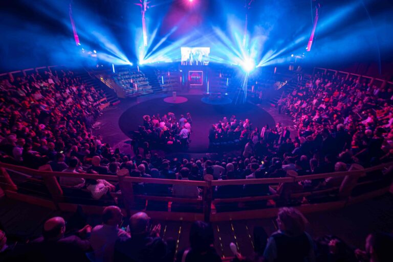 Roadshow - Plénière pour La Banque Postale DPOPN en auditorium 360° à l'Académie Fratellini, mise en lumière rose et violet, en accord avec le thème Energie Tour, vue scène avec écran et visuel en volume